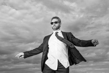 Dışarıdaki takım elbiseli kaygısız patron. Takım elbiseli patron. Takım elbiseli patronun fotoğrafı. Gökyüzü arka planında takım elbiseli patron.