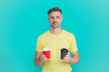 Olgun bir adam mavi üzerine kafeinsiz kahve fincanı seçer. Sabah kahvesi vakti. Yaşam tarzı konsepti. Kafeinsiz içiyorum. Çay içen adam. Sıcak bir sabah, rahatla. Kahveci adamla kahve molası. Boşluğu kopyala.