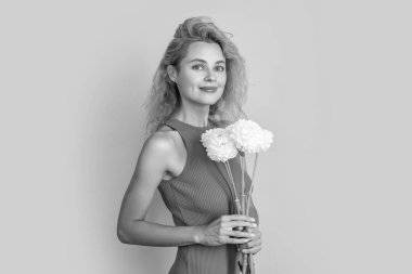 Stüdyoda bahar çiçekleriyle neşeli bir kadın. Arka planda bahar çiçekleri olan kadın. Bahar çiçekli kadın fotoğrafı. Bahar çiçekli kadın sarıda yalnız..