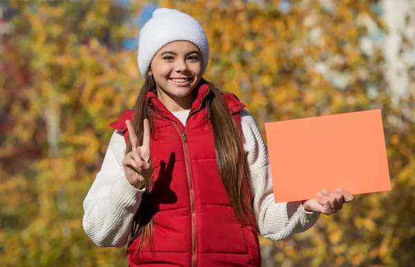 stock image fall season sale. seasonal discount for school. fall girl promoter. autumn girl promoter hold paper with copy space. teen girl promoting advertisement. autumn offer. peace.
