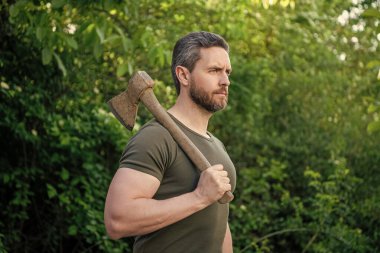 Baltalı bir adamın görüntüsü. Baltalı adam. Baltalı adam tişört giyiyor. Elinde balta olan adam..