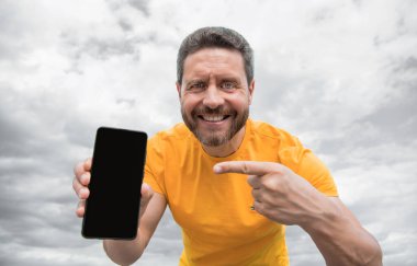 Gülümseyen adam akıllı telefon ekranını kopyalama alanı ile sunuyor.