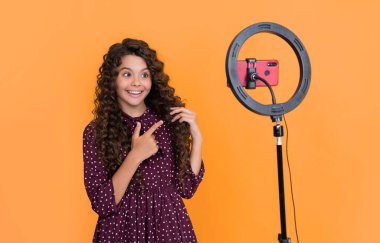 Uzun kıvırcık saçlı gülümseyen çocuk blog için video yapıyor.