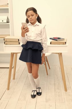 sad school girl with phone. photo of school girl with phone. school girl with phone in classroom. school girl with phone at the desk.