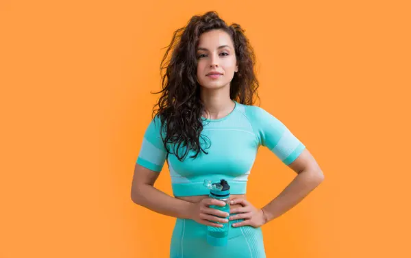 stock image fitness woman with sport bottle in studio. fitness woman hold sport hydration bottle isolated on yellow background. fitness and sport hydration.