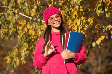 Sonbahar ders çalışma zamanıdır. Bilgi ve eğitim. Okul bilgisi. Okula dönüyorum. Sonbahar kızı okul ödevini tutuyor. Ergenlik bilgisi. Sonbahar parkındaki genç kız. Eğitim politikası.