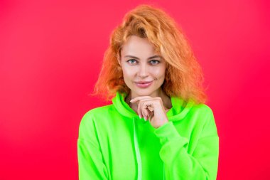 Hareketli moda kız kapüşonlu giyer. Moda kıyafetleri ve tarzı. Kazaklı beyaz bir kadın. Sıradan bir yaşam tarzı. Havalı kapüşonlu giyen kızıl saçlı kız. Pembe üzerine izole edilmiş şık bir kadın. Süper model.