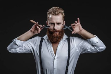 Profesyonel berber, retro traş makinesini tutar. Saç tıraşı olan yakışıklı bir kuaför. Berber dükkanı. Erkek kuaförlüğü ve berberlik. Berber dükkanındaki kuaför siyahta izole edilmiş. Kuaför. Saç stili.