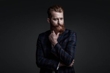 Takım elbiseli şık bir adam. Sakallı bir iş adamı. Gri yolda yabani sakallı adam. Zarif takım elbiseli hırslı bir adam. Erkekler için resmi moda. Erkek giyim modeli. Tasarımcı kıyafeti.