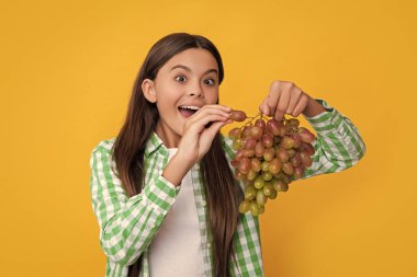 Sarı arka planda üzüm demeti olan hayrete düşmüş genç bir kız..