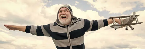 stock image happy senior man on sky background. senior man at retirement. senior retired man with toy plane outdoor.