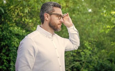 Yakışıklı iş adamı gözlüklere bakıyor doğal arka plan, kopyalama alanı.