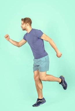 Spor adamı mavi arka planda izole edilmiş egzersiz yapıyor. Spor adamı stüdyoda koşuyor. Spor adam spor kıyafeti giyerek egzersiz yapıyor. Spor yapan adamın tam boy fotoğrafı..