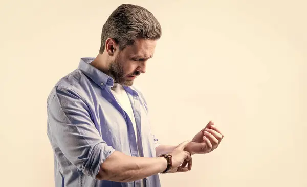 stock image mature man with pulse on wrist, copy space. man check pulse on wrist isolated on grey background. man checking pulse on wrist in studio. photo of man measuring pulse on wrist.