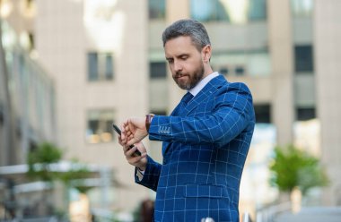 Dakik adam, nöbete geç kalma zamanını kontrol ediyor. Nöbetçi bir iş adamı. Dakik iş adamı dışarıda zamanı kontrol ediyor. İş için son gün. İş hayatına geç kalan bir iş adamı. Zaman yönetimi.