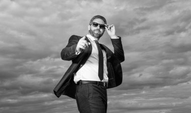 Takım elbiseli iş adamı dışarıyı işaret ediyor. Takım elbiseli iş adamı. Takım elbiseli iş adamının fotoğrafı. Gökyüzü arka planında takım elbiseli iş adamı.