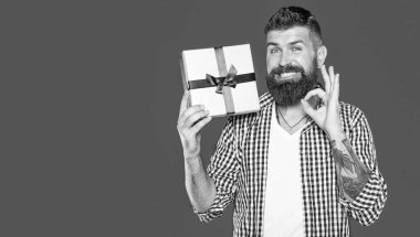 Gri arka planda hediye kutusu olan olgun sakallı adam. Tamam.