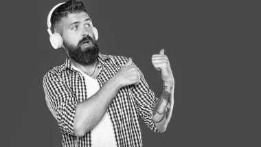 Şok olmuş sakallı adam kulaklıkla müzik dinliyor..