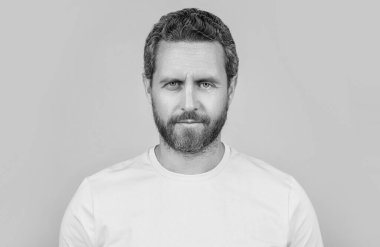 Sakallı adam arka planda sarı tişört giyiyor. Stüdyoda sarı tişört giyen bir adam. Sarı tişört giyen bir adamın fotoğrafı. Erkekler sarı tişört giyer..