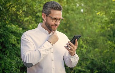 Gülümseyen iş analisti internette çalışıyor. İş analisti açık havada telefonla çalışıyor. İnternette çalışan iş analisti. İnternet üzerinde çalışan iş analistinin fotoğrafı.