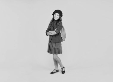 Okul çantalı mutlu çocuk. Bereli genç kız sırt çantası taşıyor. Okula dönüyorum. Bilgi günü. Eğitim konsepti. Sarı arka planda üniformalı bir çocuk. 1 Eylül. Mutlu çocukluk..