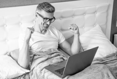 Gözlüklü olgun bir adamın laptopla yatakta çalışmasına sevindim..