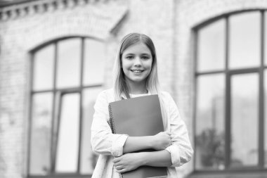 Happy teen girl back-to-school on September 1 holding books outdoors, education.