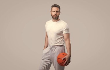 Stüdyoda ciddi bir atlet basketbolcu. Basketbolcu ve topçunun fotoğrafı. Spor giyim sektöründe basketbol oyuncusu. atlet basketbolcu gri arka planda izole.