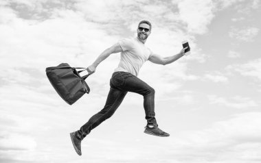 Spor çantalı, gökyüzü arka planında koşan aktif bir adam..