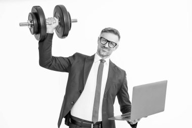 Takım elbiseli güçlü işadamı, beyaz arka planda ağır dambıl ve dizüstü bilgisayar tutuyor..