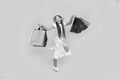 teen girl smile with shopping bags on yellow background. full length.