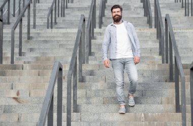 Sakallı adam aşağı iniyor. Sakallı bir adam. Merdivenlerde hippi bir adam var..