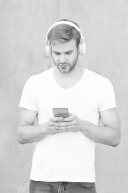 İnsan mp3 müzik listesinin kulaklıkla fotoğrafı. Adam mp3 müzik listesini açıyor. Adam dışarıda mp3 müzik listesi kullanıyor. Beyaz gömlek giyen bir adam mp3 müzik listesini seçer.