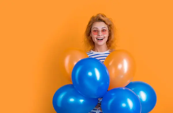 stock image party woman with balloon in sunglasses. amazed woman hold party balloons in studio. woman with balloon for party isolated on yellow background.