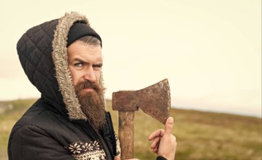 Dağda baltasını tutan sakallı bir oduncunun fotoğrafı, afiş. Sakallı adam dışarıda baltayı tutuyor. Sakallı adamın baltası var. Baltalı sakallı oduncu..