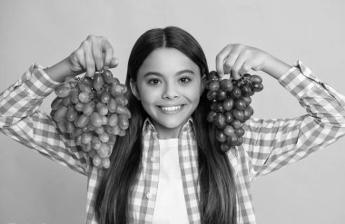 Sarı arka planda üzümlü pozitif çocuk.