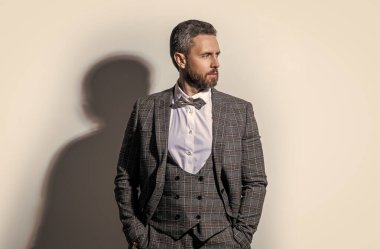 Stüdyodaki smokinli adam. Smokin giyen adamın fotoğrafı. Adam smokin resmi takım elbise giyiyor. Gri arka planda smokinli adam..