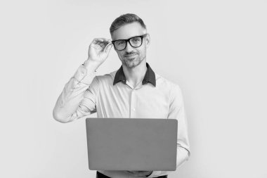 Gri arka planda bilgisayar üzerinde çalışan gözlüklü olgun bir iş adamı..