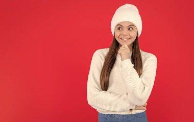 Sıcak kış örgü süveteri giyen, fotokopi çekimli mutlu genç kız. Genç kış kızı kırmızı arka planda izole edilmiş. Sıcak kış örgüsü modası.