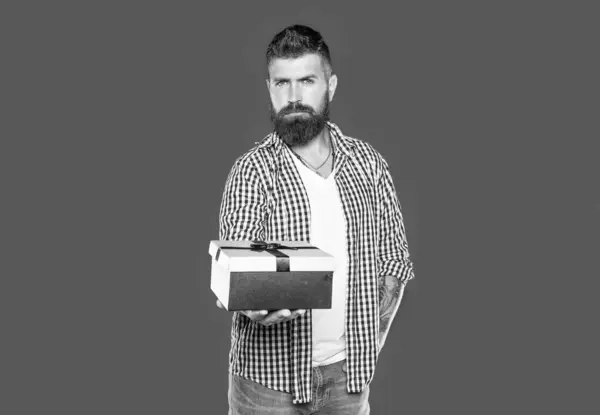 stock image mature bearded guy with gift box on grey background.