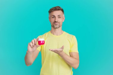 Cilt güzelliği. Erkek güzellik kozmetiği. Erkek kozmetik ürünü sunan adam. Mavi renkte yüz kremi gösteren bir adam var. Olgun adam cilt kremi kullanır. Günlük alışkanlık ve kişisel bakım. Savaş yaşlanma işaretleri.