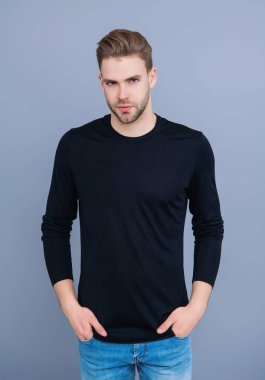 Kendine güvenen adam portresi. Erkeklerin cilt bakımı. Erkek derisi. Adamın şık bir saç kesimi var. Moda saç stili olan bir adam. Sıradan erkek tarzı. Beyazlı genç bir adam gri yolda izole edilmiş. Kaba ve yakışıklı..