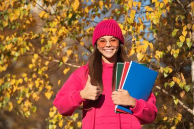 Eylül 'deki bilgi günü. Sonbahar eylül ayındayız. Eylül 'ün 1' inde okul ödevi olan genç bir kız. Genç kız açık havada düşmeyi sever. Okula dönüyorum. Genç kızların okul eğitimi. başparmak yukarı.