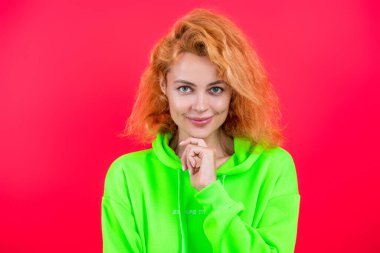 Havalı flörtçü kadın ya da kızıl saçlı manken gündelik tarz ve moda kapüşonlu parlak renkli pembe üzerine izole edilmiş..