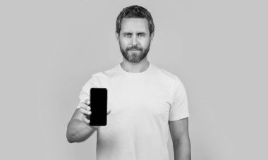 Akıllı telefon uygulaması gösteren adam sarıda izole edildi. Adam arka planda akıllı telefon uygulaması gösteriyor. Stüdyoda akıllı telefon uygulaması gösteriyor. Akıllı telefon uygulaması gösteren bir adamın fotoğrafı.