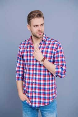 Erkek güzelliği ve saç stili. Gündelik giyinen milenyum adamı. Yakışıklı genç adam. Sıradan gömlekli bir adamın portresi. Gri üzerinde kollarını çapraz tutuyor. Tıraşsız erkek derisi. Genç model..