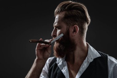 Berber retro bıçak kullanıyor. Kaba kuaför saç kesiyor. Berber dükkanında çalışan bir kuaför. Berber dükkanı. Kızıl sakallı adam. Berber dükkanındaki kuaför siyahtan soyutlanmış. Doldurulmuş sakal.