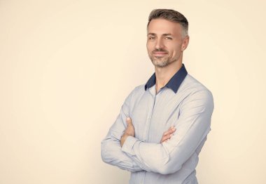 Gülümseyen olgun CEO gri arka planda iş gömleği giyer..