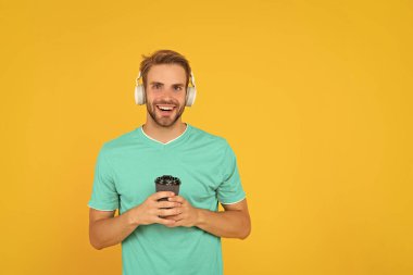 Okula dönüyorum. Kulaklıklı genç adam. Müzik aşığı. Müzik dinle. Kablosuz cihaz aksesuarı. Yeni teknoloji. Modern kulaklıklı, kahve fincanı olan mutlu bir adam. çevrimiçi eğitim.