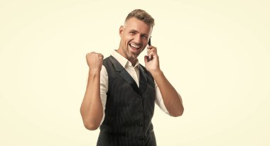 Takım elbiseli mutlu profesyonel adam cep telefonuyla konuşuyor galibiyet jestini beyaza izole ediyor..